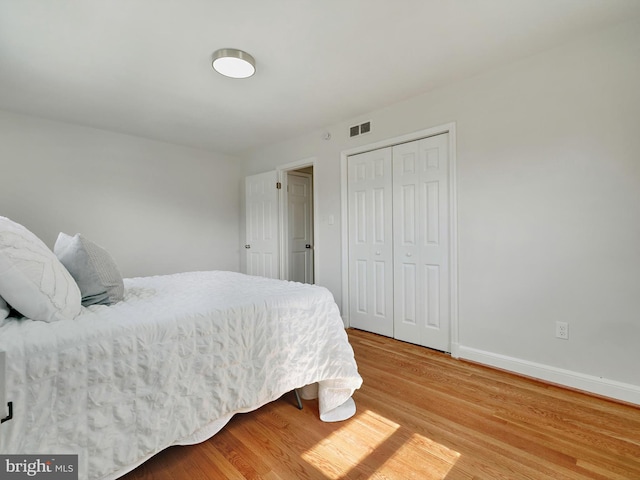 bedroom featuring a closet, visible vents, light wood-style flooring, and baseboards