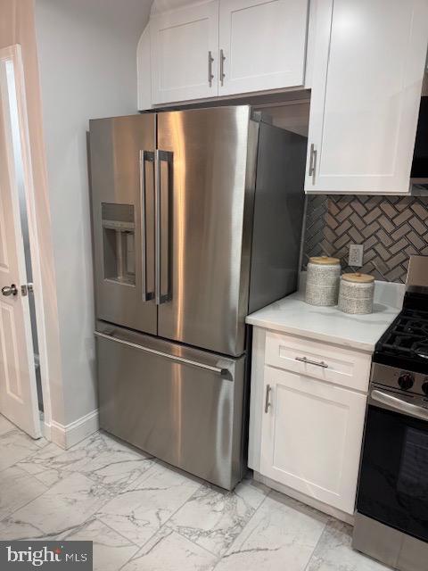 kitchen featuring marble finish floor, appliances with stainless steel finishes, white cabinets, light countertops, and decorative backsplash