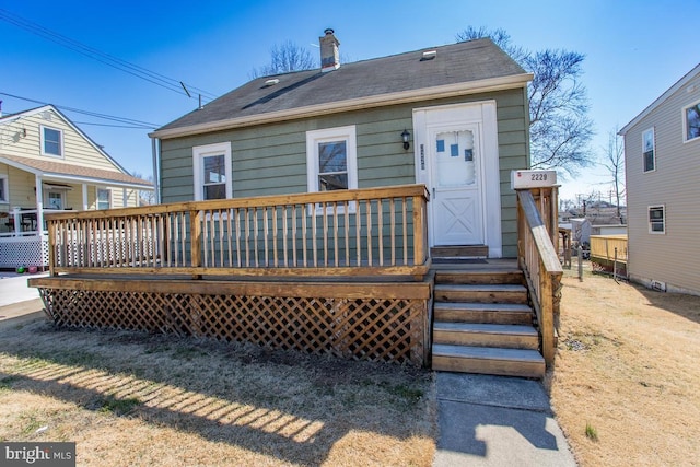 rear view of property featuring a deck and a chimney