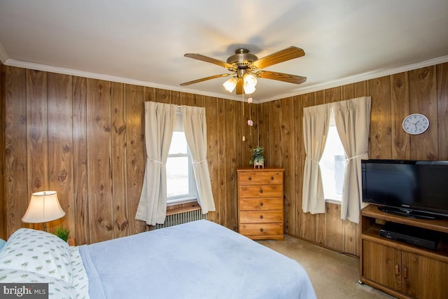 carpeted bedroom featuring crown molding, wooden walls, and ceiling fan