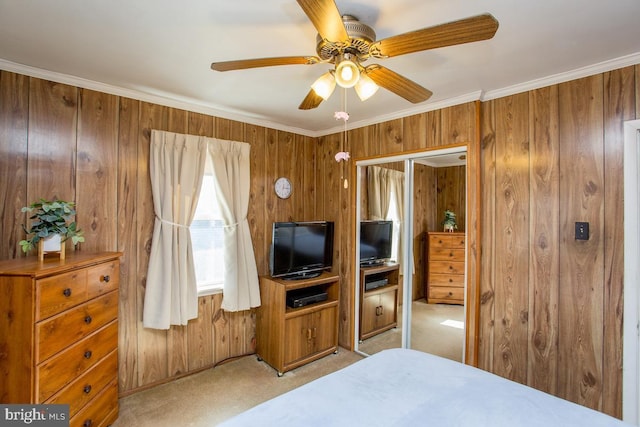 bedroom with light carpet, wooden walls, crown molding, and ceiling fan