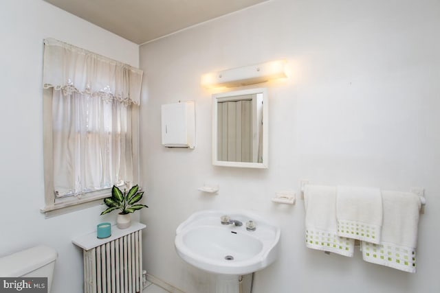 bathroom with a sink, radiator, and toilet