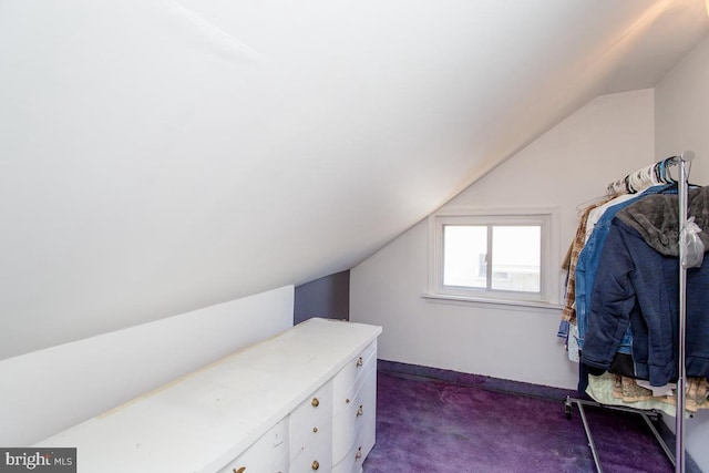 walk in closet with dark carpet and vaulted ceiling