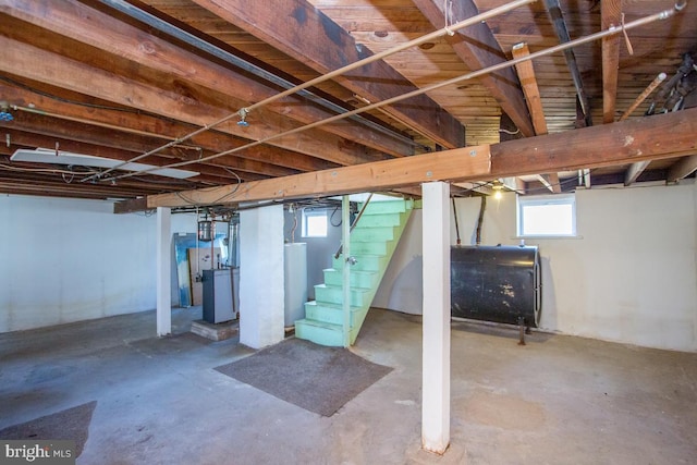 below grade area featuring stairway, heating fuel, and water heater