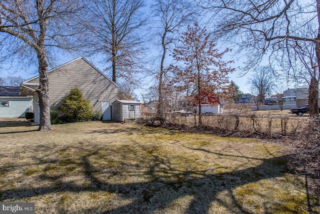 view of yard featuring a storage unit, an outdoor structure, and fence