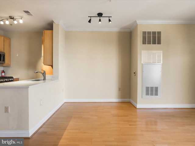 kitchen featuring a sink, visible vents, light wood finished floors, and stainless steel microwave