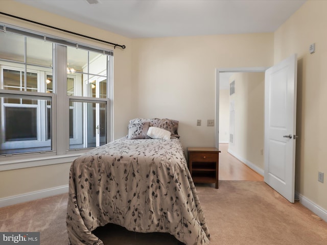 bedroom featuring visible vents, baseboards, and light carpet