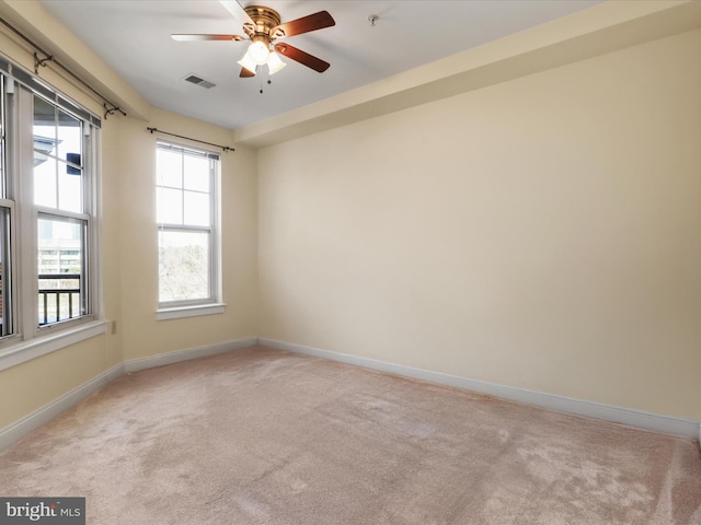 empty room featuring light carpet, visible vents, and baseboards