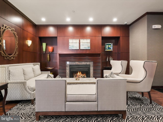 living room featuring recessed lighting, wood finished floors, and a warm lit fireplace