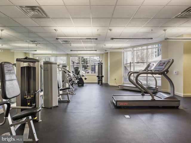 exercise room featuring a drop ceiling, visible vents, and baseboards