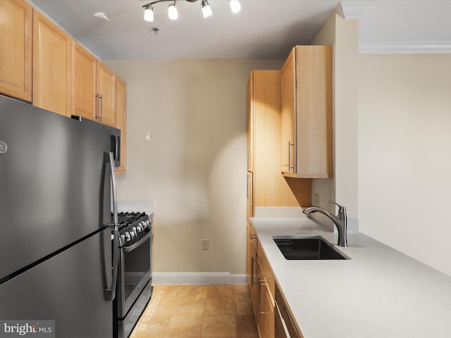 kitchen featuring baseboards, light brown cabinetry, a sink, light countertops, and appliances with stainless steel finishes