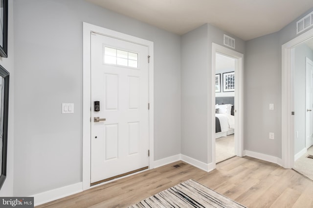 foyer entrance with light wood-style floors, visible vents, and baseboards