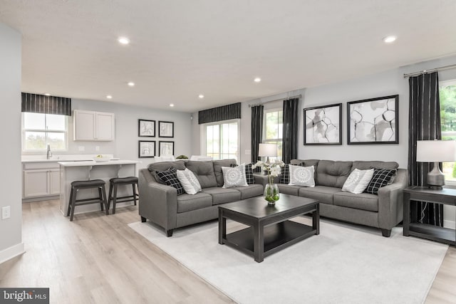 living room with a wealth of natural light, light wood-type flooring, and recessed lighting