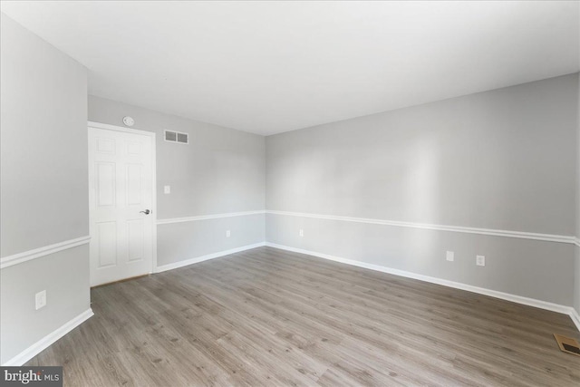 unfurnished room with visible vents, baseboards, and wood finished floors