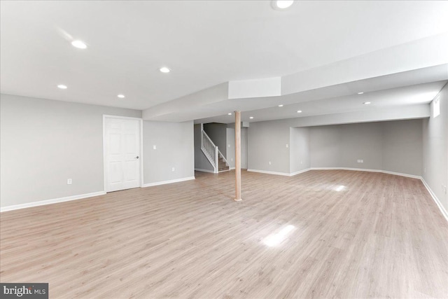 finished below grade area featuring stairs, recessed lighting, light wood-style floors, and baseboards