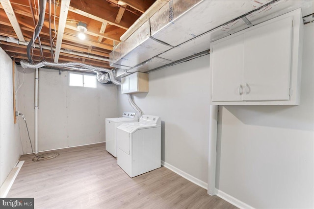 laundry room featuring washing machine and clothes dryer, cabinet space, light wood finished floors, and baseboards