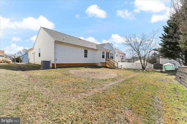 back of house with central air condition unit, a lawn, entry steps, and a fenced backyard