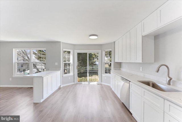 kitchen featuring dishwasher, white cabinets, light wood-type flooring, and a sink