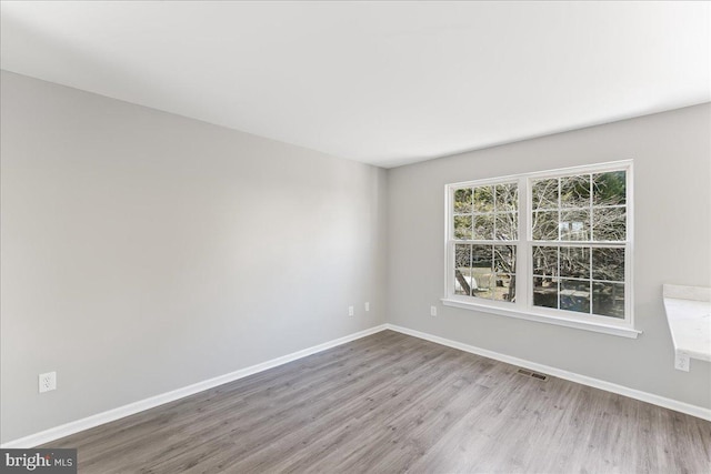 spare room with visible vents, wood finished floors, and baseboards