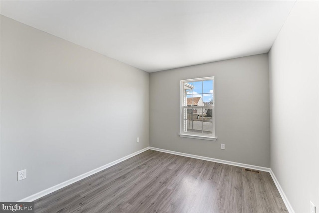 unfurnished room with visible vents, baseboards, and wood finished floors