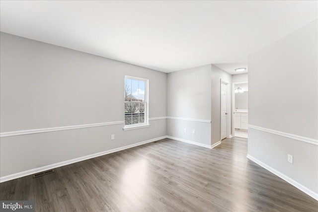 spare room featuring visible vents, baseboards, and wood finished floors