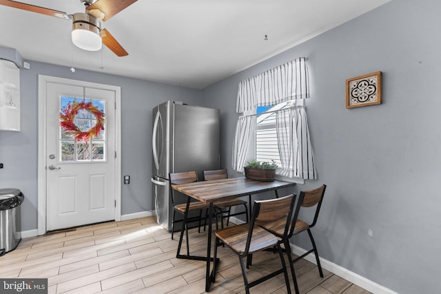 dining room with a ceiling fan, baseboards, and wood tiled floor