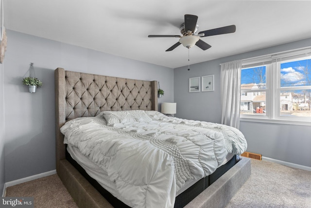 carpeted bedroom with visible vents, baseboards, and a ceiling fan