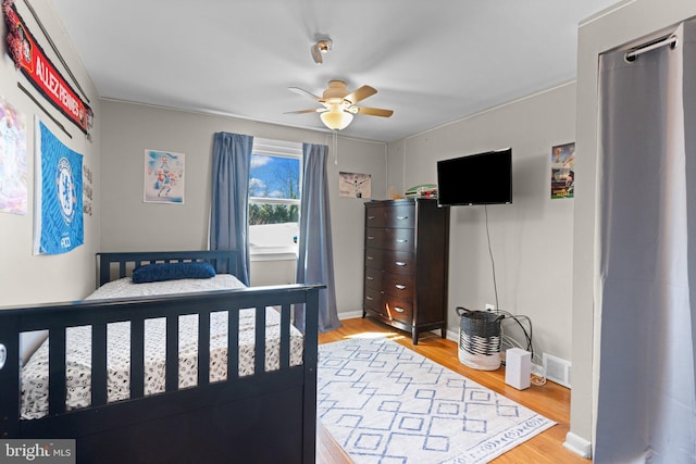 bedroom with light wood finished floors, visible vents, ceiling fan, and baseboards