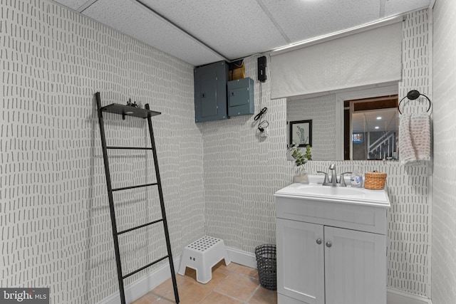 bathroom with vanity, electric panel, a drop ceiling, tile patterned flooring, and walk in shower