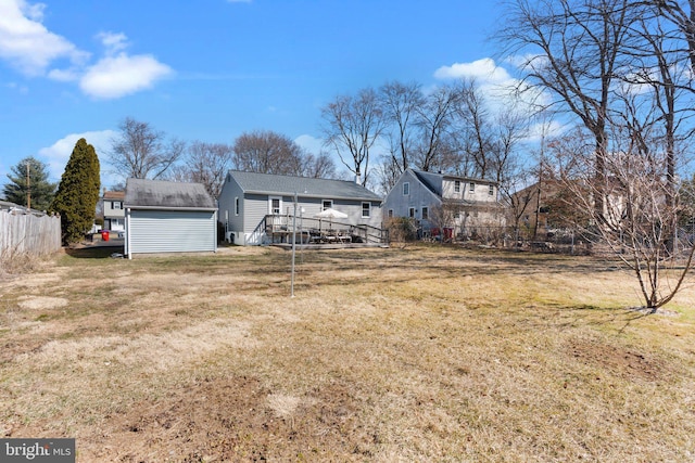 back of house with fence, an outdoor structure, a storage unit, a deck, and a lawn