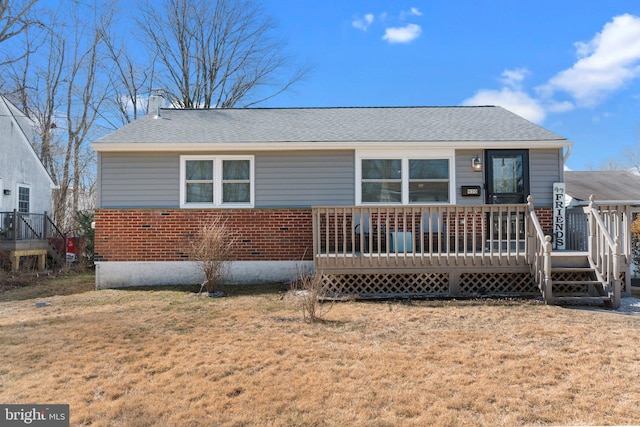 back of house with roof with shingles, a yard, a chimney, a deck, and brick siding