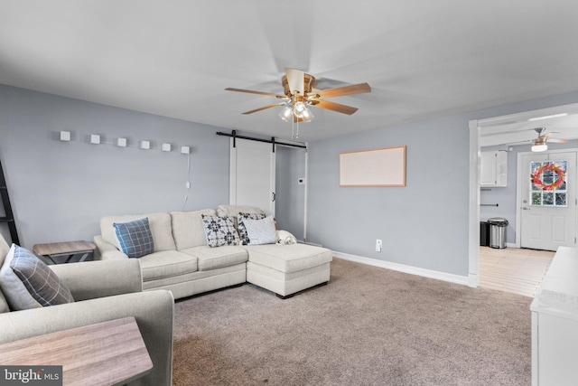 living room with light carpet, ceiling fan, baseboards, and a barn door