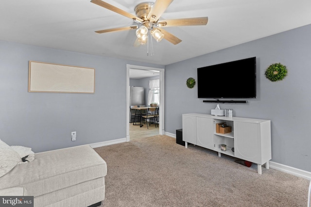 carpeted living room with baseboards and a ceiling fan