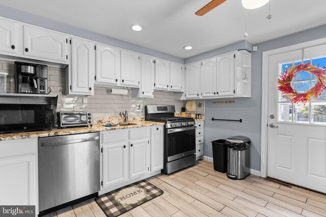 kitchen featuring light stone counters, a sink, white cabinetry, appliances with stainless steel finishes, and a toaster