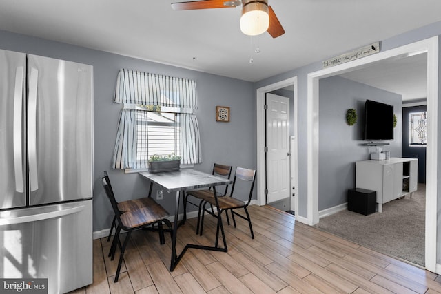 dining space with baseboards, light wood-style flooring, and a ceiling fan