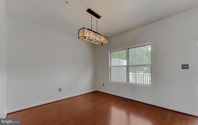 unfurnished room featuring wood finished floors, visible vents, and baseboards