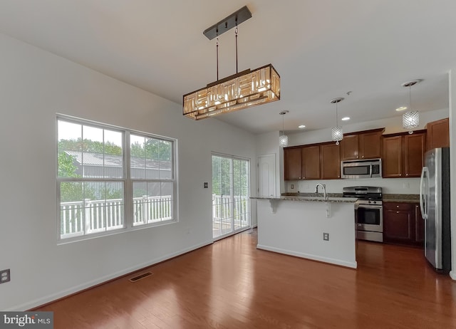 kitchen featuring visible vents, stainless steel appliances, baseboards, dark wood-style flooring, and hanging light fixtures