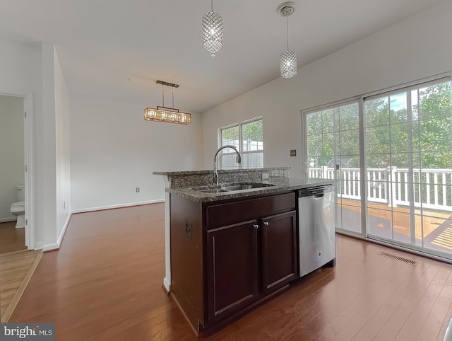 kitchen featuring dark wood-style floors, visible vents, dark stone counters, a sink, and dishwasher