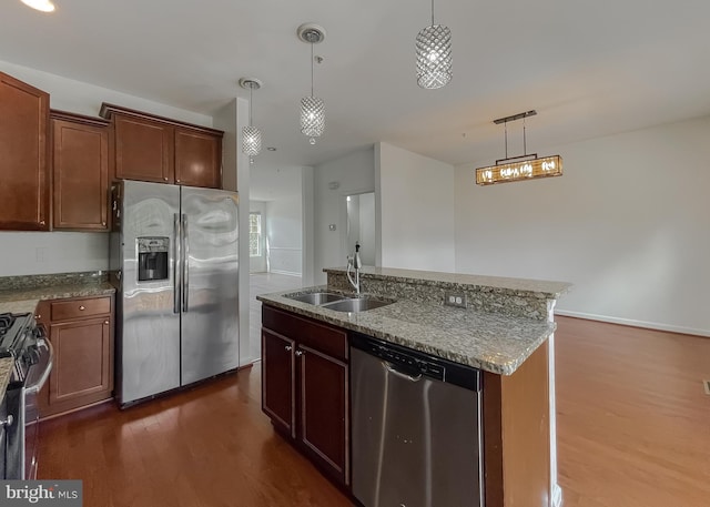 kitchen with a sink, stone countertops, decorative light fixtures, dark wood finished floors, and stainless steel appliances