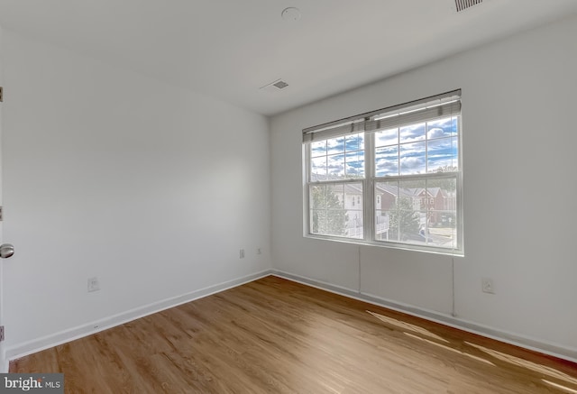 unfurnished room featuring light wood-type flooring, baseboards, and visible vents