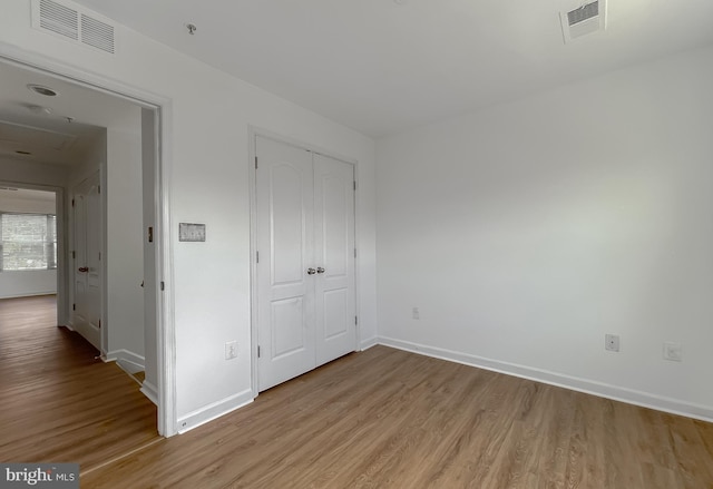 unfurnished bedroom with a closet, visible vents, light wood-type flooring, and baseboards