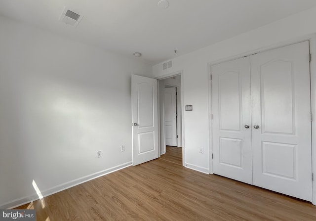 unfurnished bedroom with a closet, visible vents, baseboards, and light wood finished floors