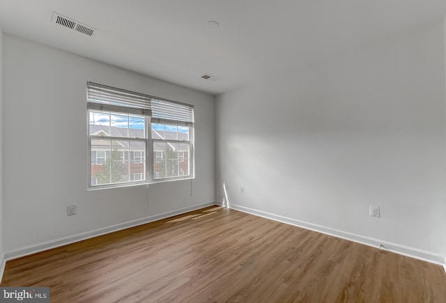 empty room featuring visible vents, baseboards, and wood finished floors