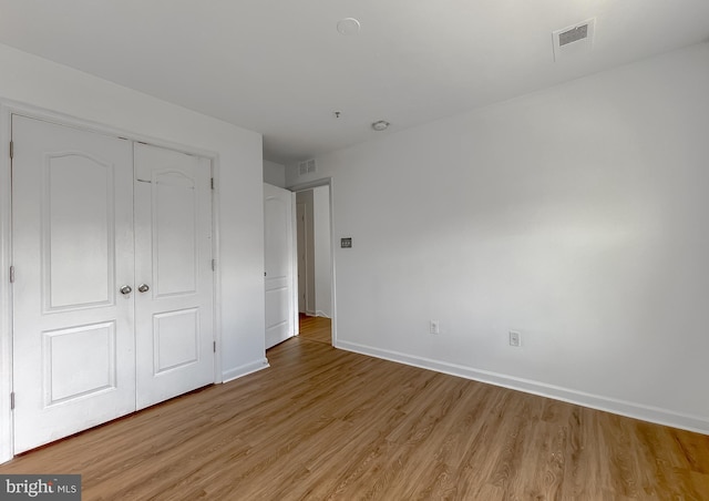 unfurnished bedroom featuring baseboards, visible vents, a closet, and light wood-type flooring