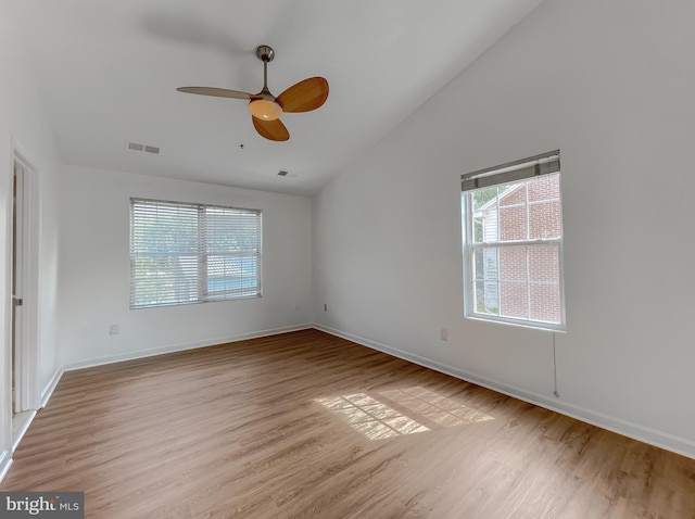 unfurnished room with visible vents, baseboards, vaulted ceiling, wood finished floors, and a ceiling fan