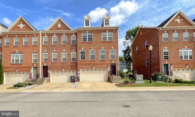 townhome / multi-family property with brick siding, driveway, and a garage