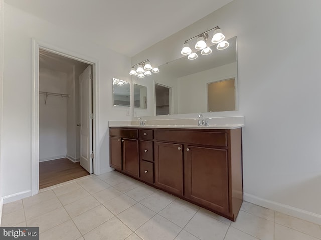 bathroom with double vanity, baseboards, a sink, and tile patterned flooring