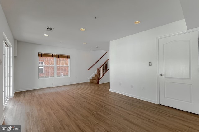 spare room featuring stairway, wood finished floors, visible vents, baseboards, and recessed lighting