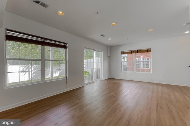 empty room with light wood-style floors, visible vents, and baseboards