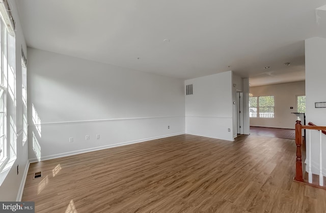 spare room with wood finished floors, visible vents, and baseboards